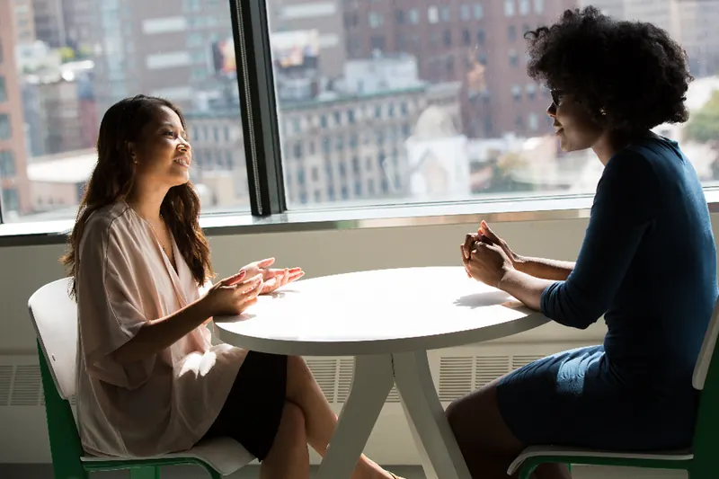 Deux personnes échangeant autour d'une table, lors d'un rendez-vous